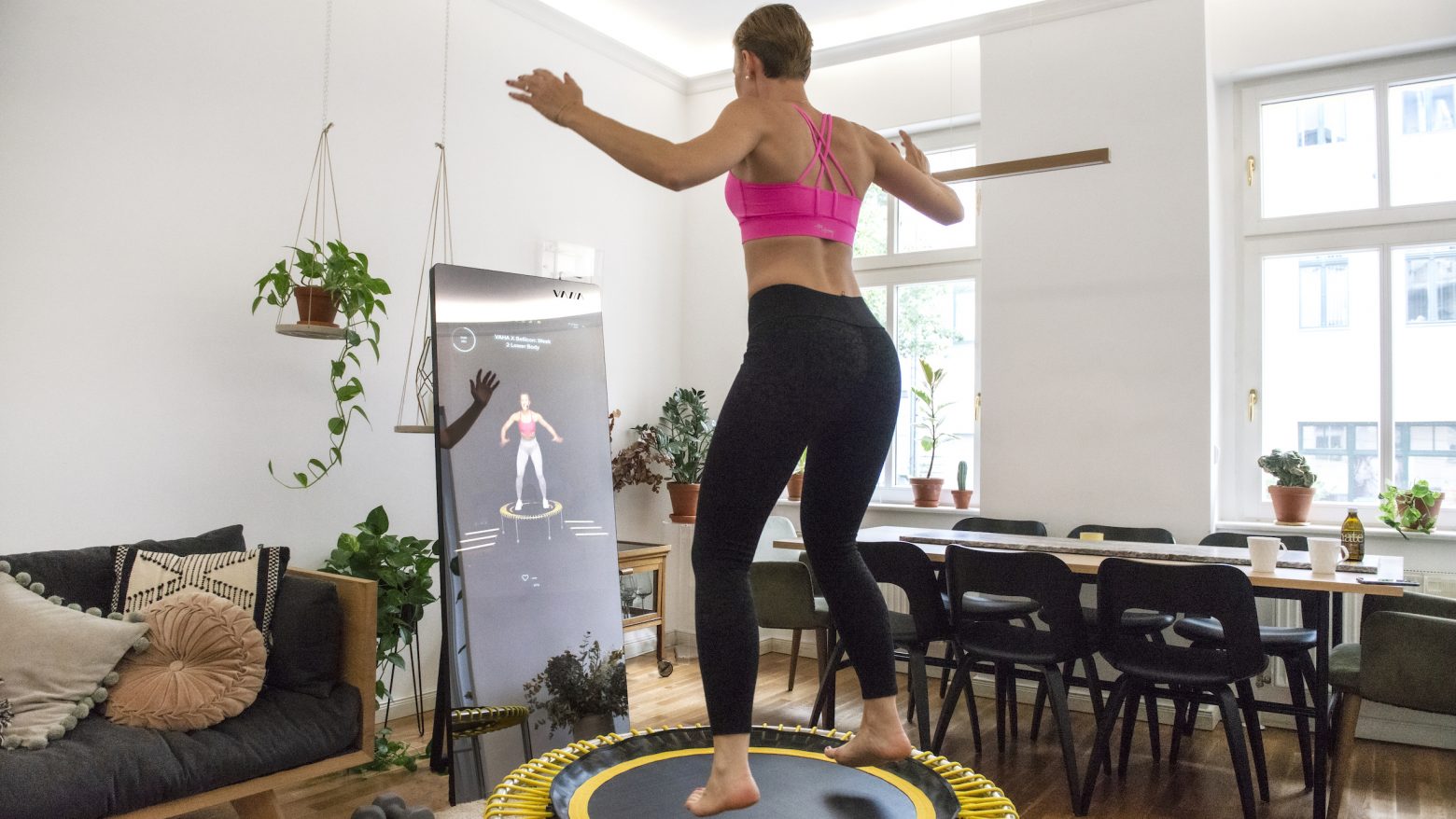 Frau trainiert mit dem VAHA Fitnessspiegel und dem bellicon Trampolin